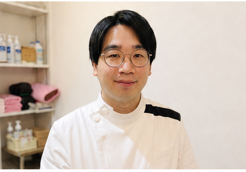 白衣を着て微笑む眼鏡の施術者